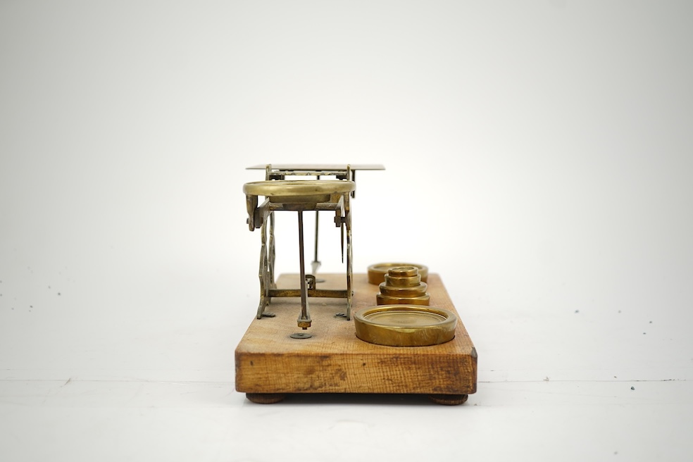 A Sampson Mordan & Co. set of brass postal scales on an oak base with weights, 27cm wide, with engraved prices for Inland Letter Post, etc.
